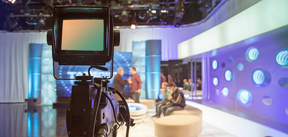 Television studio with camera and lights - recording TV show. Shallow depth of field - focus on camera